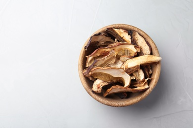 Photo of Bowl of dried mushrooms on color background, top view. Space for text