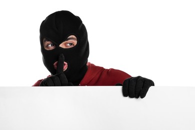 Photo of Thief in balaclava showing hush gesture on white background