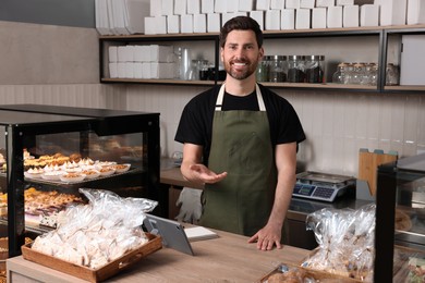 Photo of Happy seller at cashier desk in bakery shop