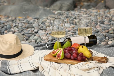 Photo of White wine and fresh fruits on picnic blanket outdoors
