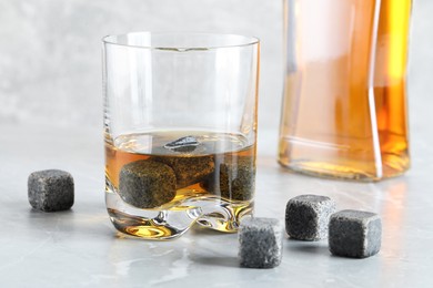 Whiskey stones and drink on light marble table, closeup