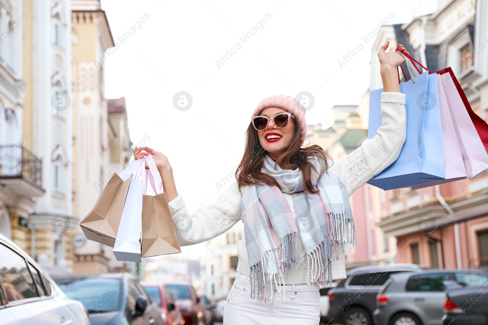 Photo of Beautiful young woman with shopping bags on city street