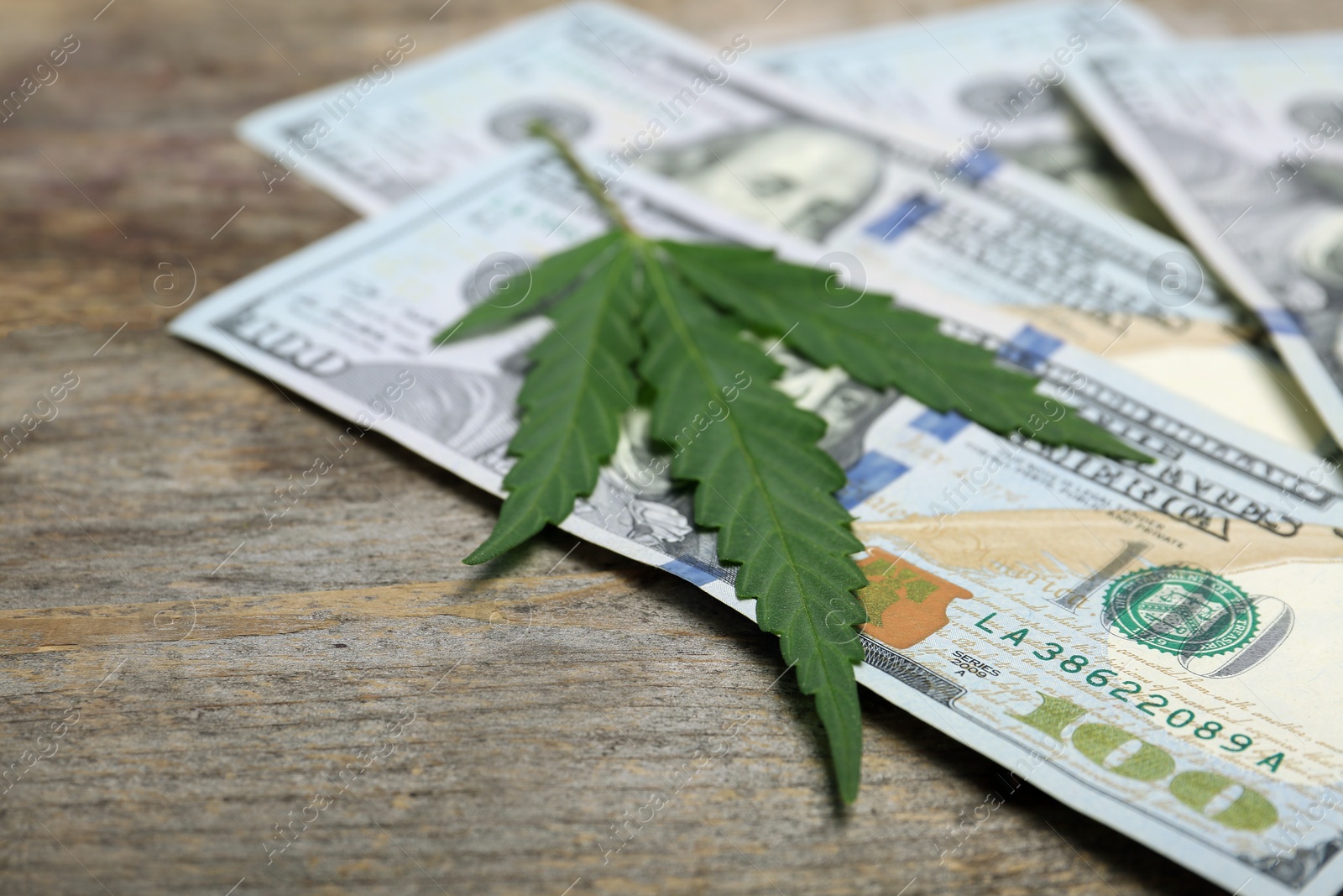 Photo of Hemp leaf and money on wooden table, closeup