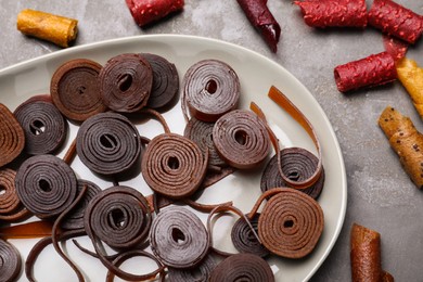 Photo of Delicious fruit leather rolls on grey table, flat lay