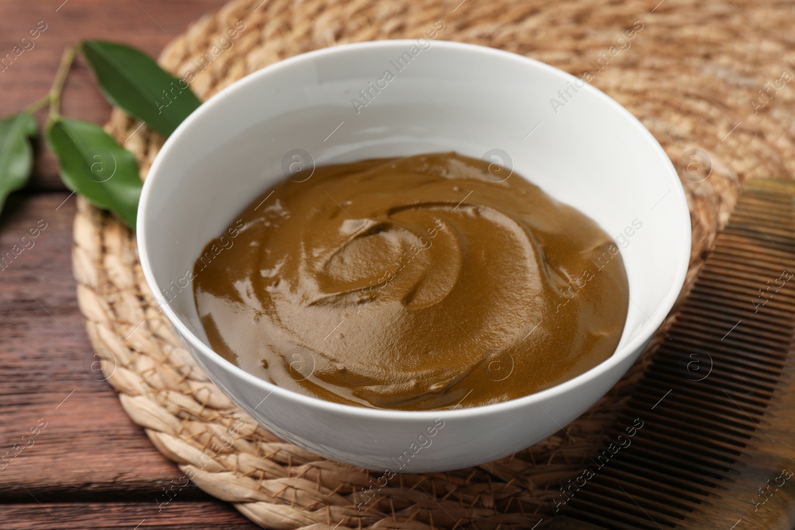 Photo of Bowl of henna cream on wooden table, closeup. Natural hair coloring