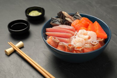 Photo of Delicious mackerel, salmon, shrimps and tuna served with funchosa, soy sauce and wasabi on grey table. Tasty sashimi dish