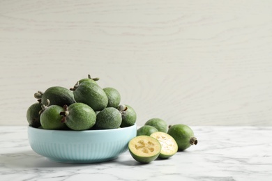 Photo of Fresh green feijoa fruits on white marble table, space for text