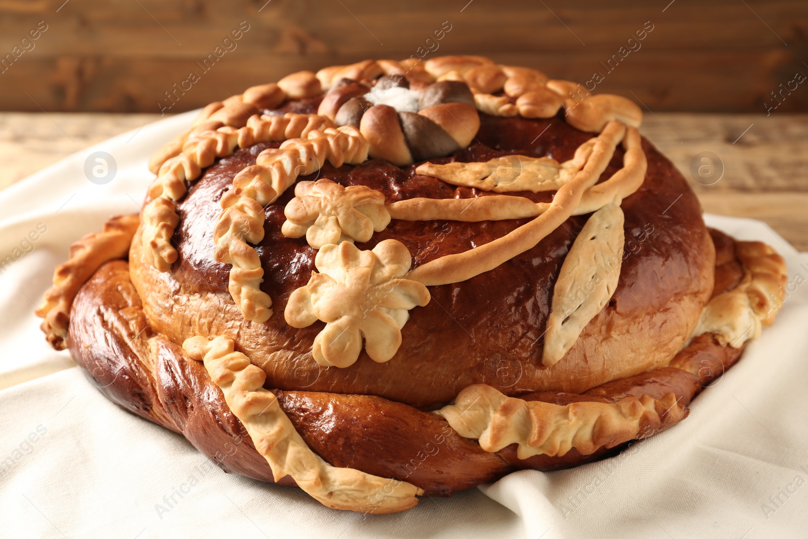 Photo of Korovai on tablecloth, closeup. Ukrainian bread and salt welcoming tradition