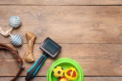 Pet toys, bowl and accessories on wooden table, flat lay. Space for text