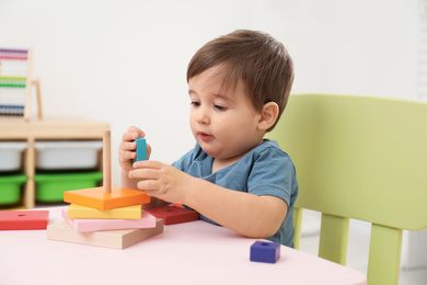 Photo of Little child playing with toy pyramid at table