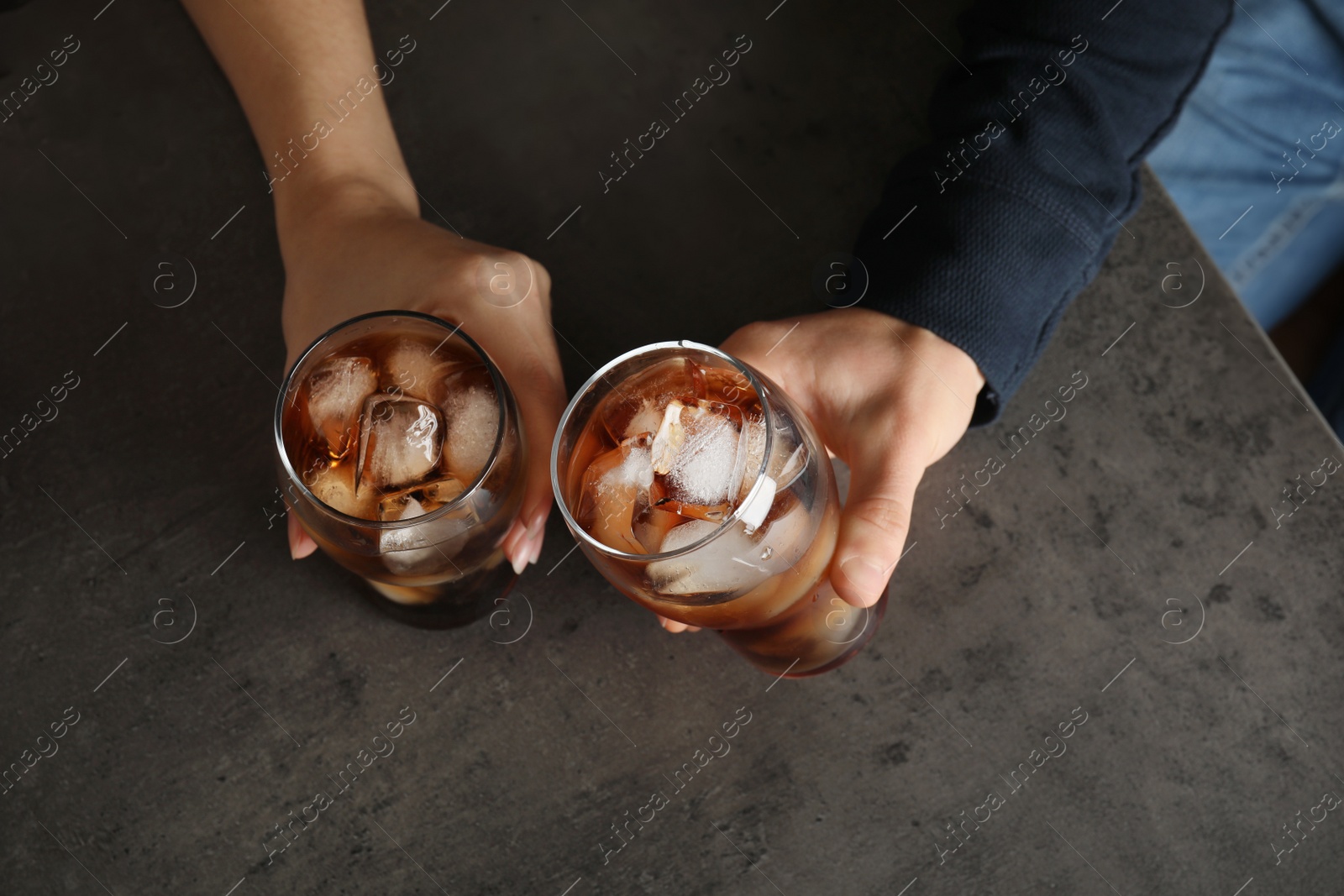Photo of Friends with glasses of tasty refreshing cola at grey table, top view