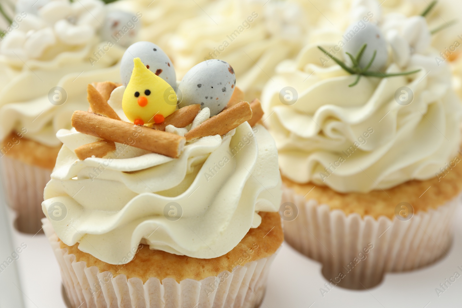 Photo of Tasty Easter cupcakes with vanilla cream in box, closeup