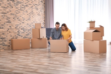 Couple unpacking cardboard box in their new house. Moving day