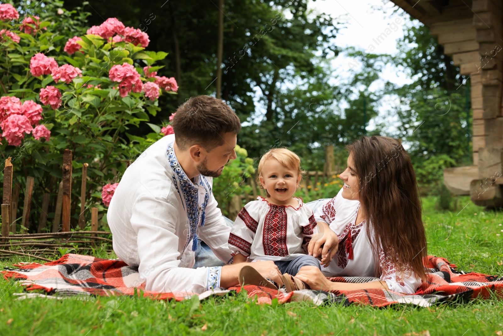 Photo of Happy family in Ukrainian national clothes on green grass outdoors