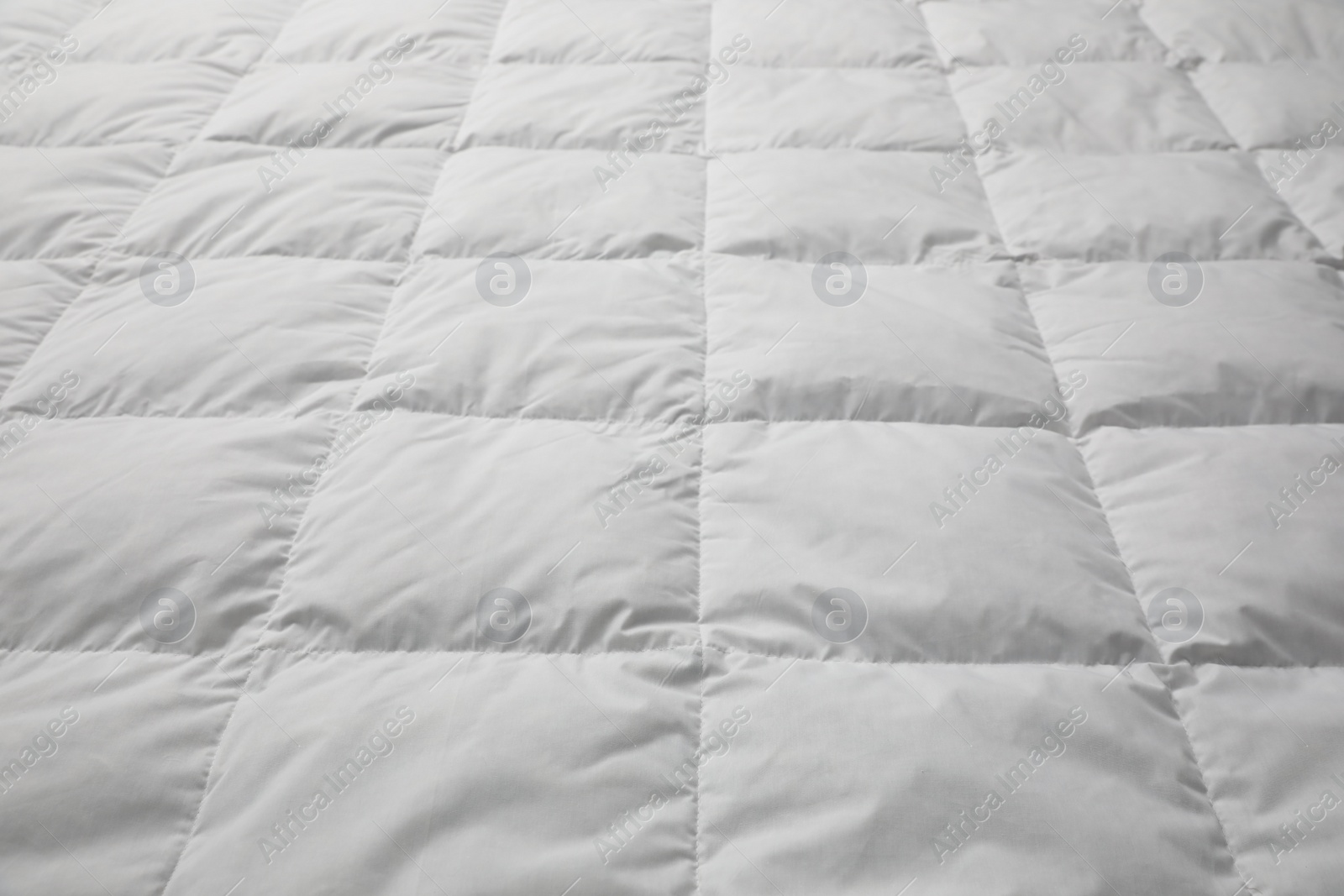 Photo of Soft quilted blanket as background, closeup view