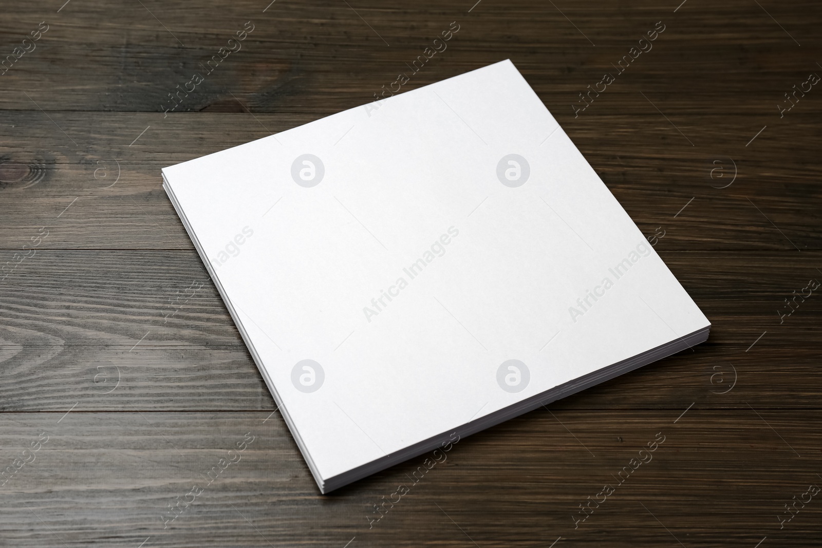 Photo of Stack of blank paper sheets on wooden table. Brochure design