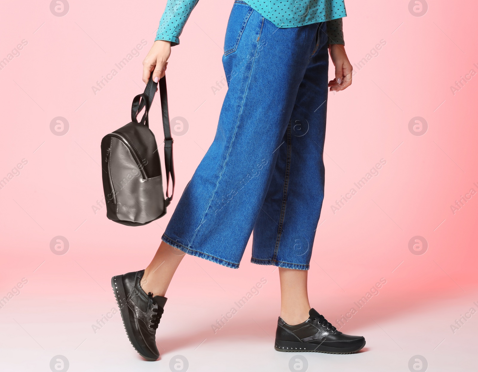 Photo of Fashionable woman in stylish shoes with backpack on color background