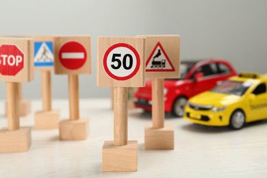 Photo of Miniature road signs and cars on white table. Driving school