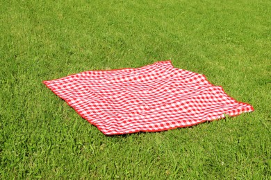 Photo of Checkered picnic tablecloth on fresh green grass outdoors