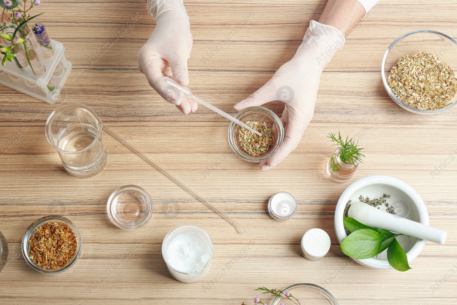 Photo of Scientist developing cosmetic product at wooden table in laboratory, top view