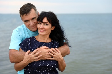 Happy mature couple spending time together on sea beach. Space for text