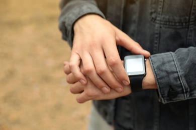 Photo of Man using stylish smart watch outdoors, closeup
