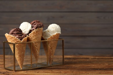 Photo of Tasty ice cream scoops in waffle cones on wooden table, closeup. Space for text