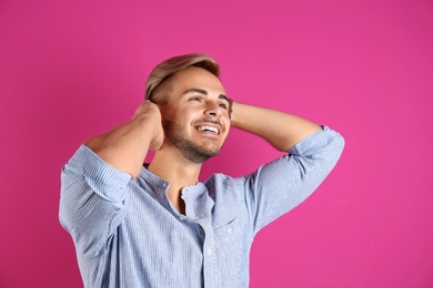 Photo of Young man with trendy hairstyle on color background