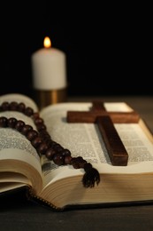 Photo of Church candle, Bible, rosary beads and cross on wooden table, closeup