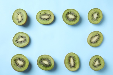 Photo of Frame made of fresh kiwis on light blue background, top view. Space for text