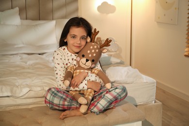Photo of Little girl with toy deer in bedroom lit by night lamp