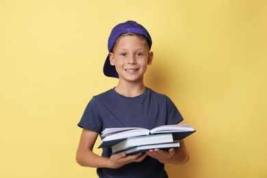 Portrait of cute little boy reading book on yellow background