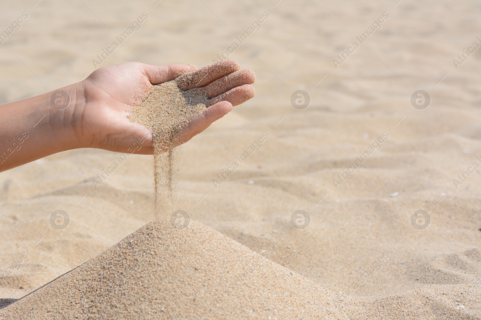 Photo of Child pouring sand from hand on beach, closeup with space for text. Fleeting time concept