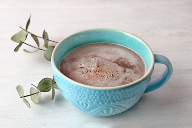 Photo of Cup with delicious hot cocoa drink on table