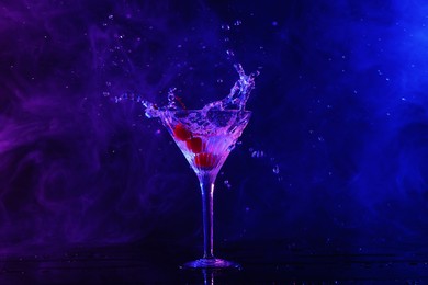 Martini splashing out of glass on table in neon lights