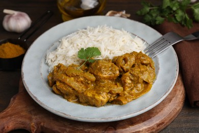 Photo of Delicious chicken curry with rice on wooden table, closeup