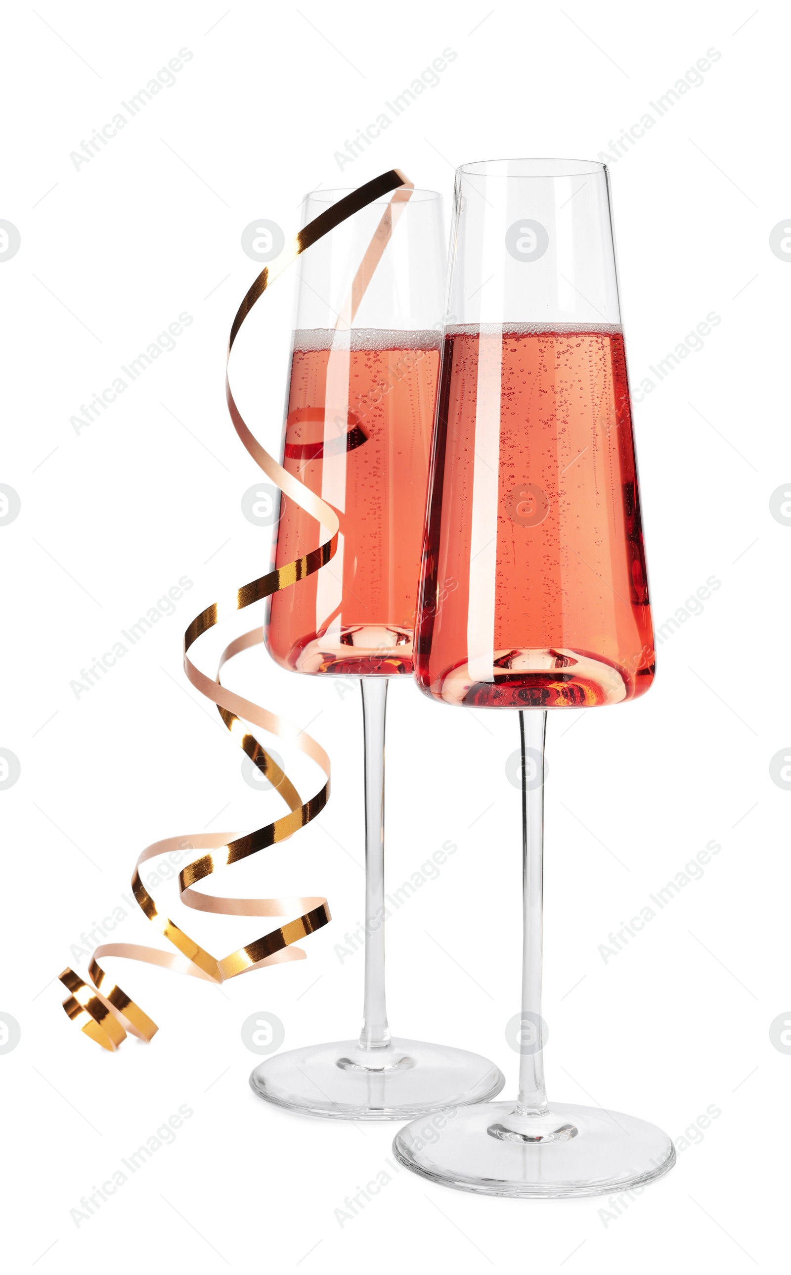 Photo of Glasses of rose champagne with gold streamer isolated on white