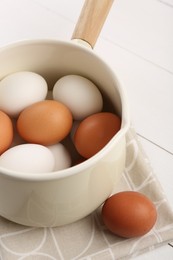 Photo of Unpeeled boiled eggs in pan on white table, closeup