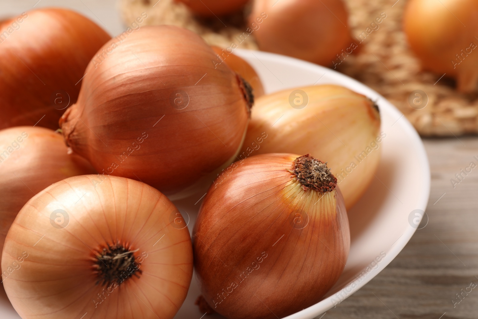 Photo of Many ripe onions on wooden table, closeup