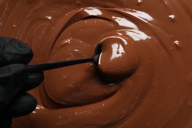 Person making tasty milk chocolate paste, top view