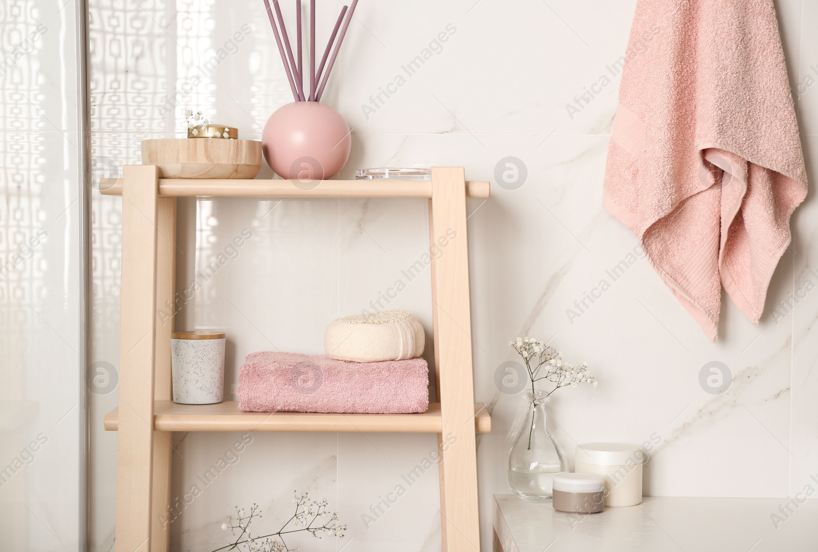 Photo of Shelving unit with towel and decorative elements in bathroom interior