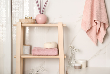 Shelving unit with towel and decorative elements in bathroom interior