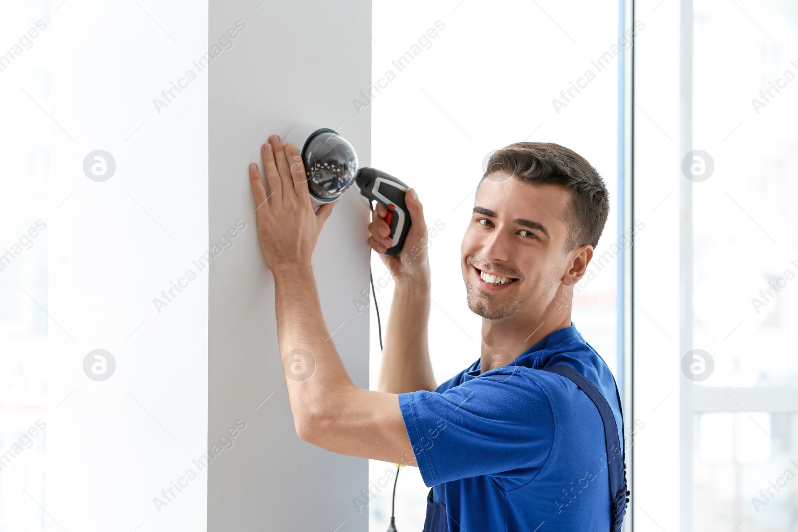 Photo of Technician installing CCTV camera on wall indoors