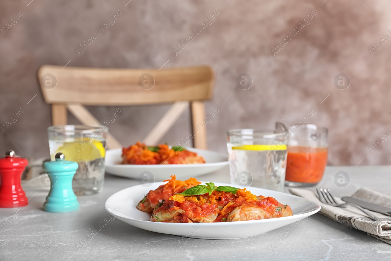 Photo of Plate with stuffed cabbage leaves in tomato sauce on table