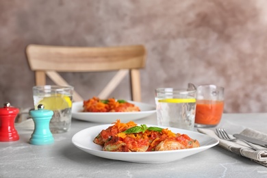 Photo of Plate with stuffed cabbage leaves in tomato sauce on table