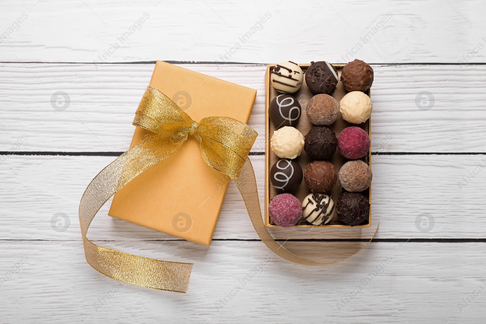 Open box with delicious chocolate candies on white wooden table, top view Photo of Open box with delicious chocolate candies on white wooden table, top view