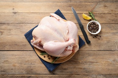 Photo of Fresh raw chicken with spices and knife on wooden table, flat lay