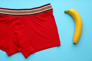 Photo of Men's underwear and banana on light blue background, flat lay. Potency problem concept