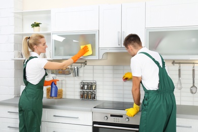 Team of janitors cleaning kitchen in house