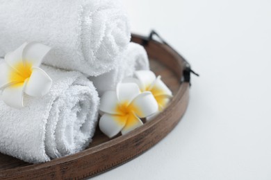 Photo of Tray with rolled bath towels on white table, closeup. Space for text